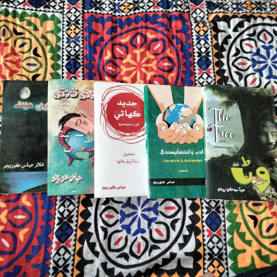 Five books by Abbas Korejo displayed on traditional Ajrak cloth